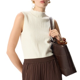 Model wearing Whistles cream sleeveless ribbed mock-neck top, styled with a brown pleated skirt and dark brown tote bag.