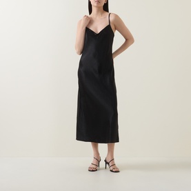 Model wearing Vince Satin Slip Dress in black, V-neckline, slim straps, midi length, styled with strappy heeled sandals.
