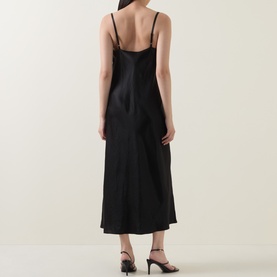 Model wearing Vince Satin Slip Dress in black, slim straps, midi length, smooth satin finish. Styled with black strappy heeled sandals.