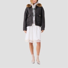 Model wearing Maje dark grey short jacket with faux fur trim hood, styled with white graphic hoodie and white midi skirt
