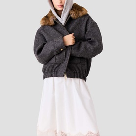 Model wearing Maje dark grey wool bomber jacket with faux fur collar and gold-tone buttons, styled with white midi dress and grey hood