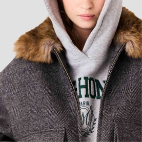 Model wearing Maje dark grey textured coat with faux fur collar, styled with grey graphic hoodie underneath