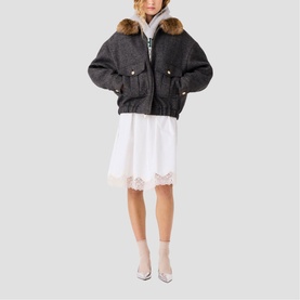 Model wearing Maje dark grey oversized jacket with fur collar, styled with white lace-hem mini dress and silver heels