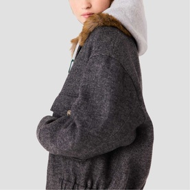 Model wearing Maje dark grey textured oversized jacket with faux fur collar trim, styled with white hoodie underneath