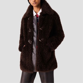 Model wearing Maje dark brown curly faux fur duffle coat with toggle fastenings, styled with black leather trousers and red tie