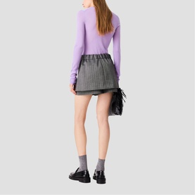 Model wearing Maje Womens French Dress in red, styled with grey mini skirt, lavender knit top, and black loafers, rear view.