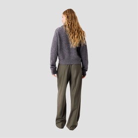 Model wearing Maje red knit sweater, shown from behind, styled with olive wide-leg trousers