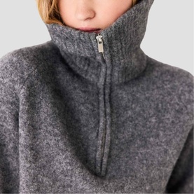 Model wearing Maje red high-neck zip-up knit jumper, shown in close-up detail of zip and funnel collar