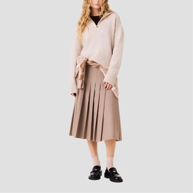Model wearing Maje clear pleated midi skirt with half-zip knit top and black loafers