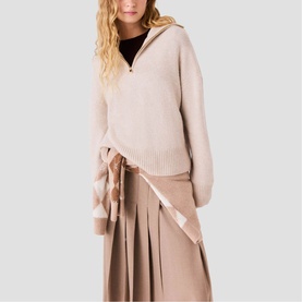 Model wearing Maje cream zip-neck knit sweater with pleated skirt and plaid scarf detail