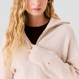 Model wearing Maje cream knit jumper with zip collar detail and ribbed cuffs, layered over a dark turtleneck