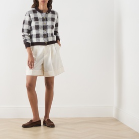Model wearing Barbour International multi check cardigan with cream shorts and brown loafers