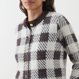Model wearing Barbour International multi check cardigan with gold button fastening, fluffy knit texture in dark brown and cream plaid pattern.