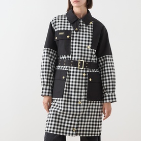 Model wearing Barbour International Gea Gingham Showerproof Coat in black, featuring gingham pattern, patch pockets, and gold-buckle belt.