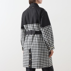 Model wearing Barbour International Gea Gingham Showerproof Coat in black, rear view showing gingham panel, adjustable belt and press-stud cuffs.