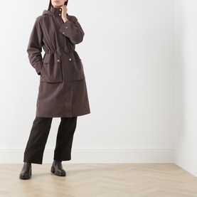 Model wearing Barbour International truffle coat with gold buttons and hood, styled with black wide-leg trousers and ankle boots
