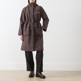 Model wearing Barbour International truffle hooded longline coat with drawstring waist, styled with black wide-leg trousers and black ankle boots