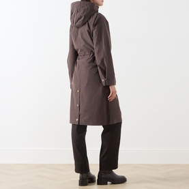 Model wearing Barbour International truffle hooded coat, shown from behind, styled with black wide-leg trousers and black ankle boots