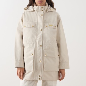 Model wearing Barbour International Molina Showerproof Short Jacket in Moonbeam with detachable hood, chest flap pockets and gold snap buttons.