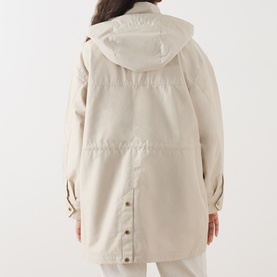 Model wearing Barbour International Molina Showerproof Short Jacket in Moonbeam, rear view showing detachable hood and studded back vent.