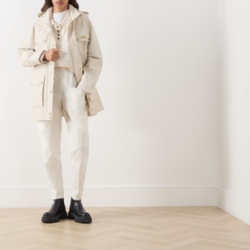 Model wearing Barbour International Molina Showerproof Short Jacket in Moonbeam with cream trousers and black chunky Chelsea boots.