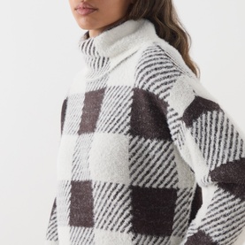 Model wearing Barbour International multi check turtleneck dress in cream and dark brown buffalo plaid knit, close-up detail view