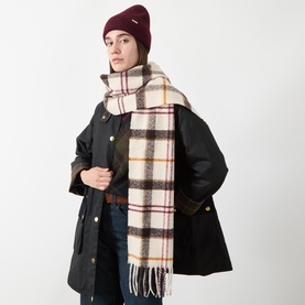 Model with Barbour Olivia Beanie Hat & Scarf Gift Set in multi; burgundy ribbed beanie and cream tartan tasselled scarf, styled with dark coat