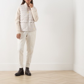 Model wearing Barbour International Ari Hybrid Quilted Jacket in Moonbeam with cream knit sleeves, styled with ivory trousers and dark ankle boots.