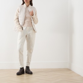 Model wearing Barbour International Ari Hybrid Quilted Jacket in Moonbeam with cream trousers and black chunky Chelsea boots.