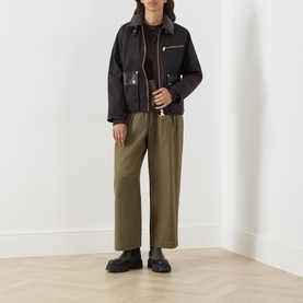 Model wearing Barbour International dark brown cotton jacket with zip details, styled with khaki wide-leg trousers and black chunky loafers