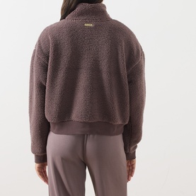 Model wearing Barbour International truffle borg fleece jacket, back view, styled with taupe wide-leg trousers