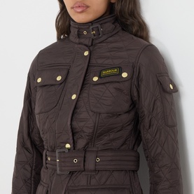 Model wearing Barbour International quilted jacket in Truffle, featuring gold-tone snap buttons, chest pockets, and belted waist.