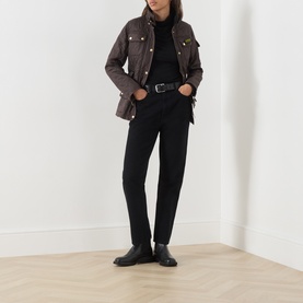 Model wearing Barbour International truffle quilted jacket with gold press-stud buttons, styled with black jeans, turtleneck and ankle boots.