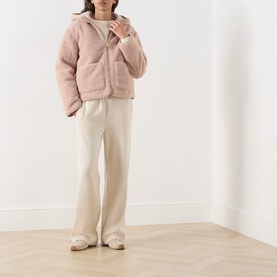 Model wearing Barbour International Ramona Zip-Up Fleece Jacket in Nutmeg, sherpa fleece with fixed hood and patch pockets, styled with cream