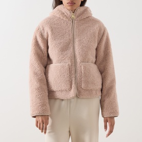 Model wearing Barbour International Ramona Zip-Up Fleece Jacket in Nutmeg, sherpa fleece with fixed hood and patch pockets, styled with cream trousers