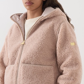 Model wearing Barbour International Ramona Zip-Up Fleece Jacket in Nutmeg, sherpa fleece with gold zip, fixed hood and patch pockets visible.