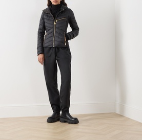Model wearing Barbour International Salengro Quilted Jacket in black with gold-toned hardware, styled with black trousers and chunky boots.