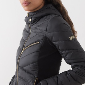 Model wearing Barbour International Salengro Quilted Jacket in black, showing stretch side panels, gold-toned zip and logo patch detail.