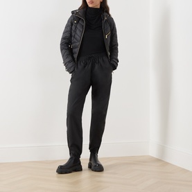 Model wearing Barbour International Salengro Quilted Jacket in black with gold-toned hardware, styled with black trousers and chunky boots.