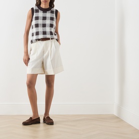 Model wearing Barbour International multi gingham knit sleeveless top with cream shorts and brown loafers.