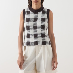 Model wearing Barbour International multi check knit sleeveless vest top, styled with white wide-leg trousers