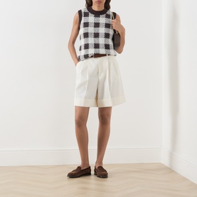Model wearing Barbour International multi check knit vest, styled with cream wide-leg shorts and brown loafers.