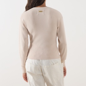 Model wearing Barbour International Cyrus Dropped-Shoulder Sweater in Nutmeg, rear view showing metal logo plaque, styled with white trousers.
