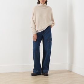 Model wearing Barbour International Moonbeam knit turtleneck, styled with dark blue wide-leg cargo jeans and black loafers