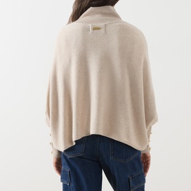 Model wearing Barbour International moonbeam knit poncho, back view, styled with blue denim cargo jeans.