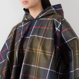 Model wearing Barbour poncho in multi tartan check with hood, small embroidered logo detail visible on chest