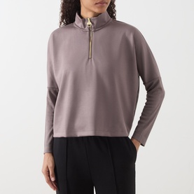 Model wearing Barbour International Kemora Logo Half-Zip Sweatshirt in Truffle with gold-toned zip, styled with black trousers.