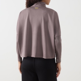 Model wearing Barbour International Kemora Logo Half-Zip Sweatshirt in Truffle, back view, gold-toned zip, long sleeves, styled with black trousers.