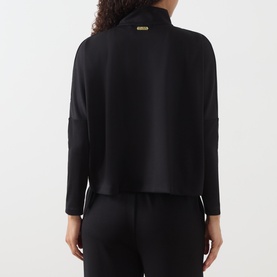 Model wearing Barbour International Kemora Logo Half-Zip Sweatshirt in black, back view, gold-toned zip, long sleeves, styled with black trousers.