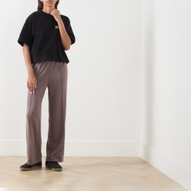 Model wearing Barbour International black cotton T-shirt with taupe wide-leg trousers and black flat shoes.